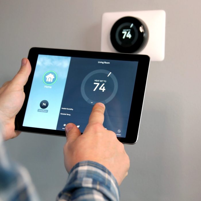 Man is Adjusting a temperature using a tablet with smart home app in modern living room