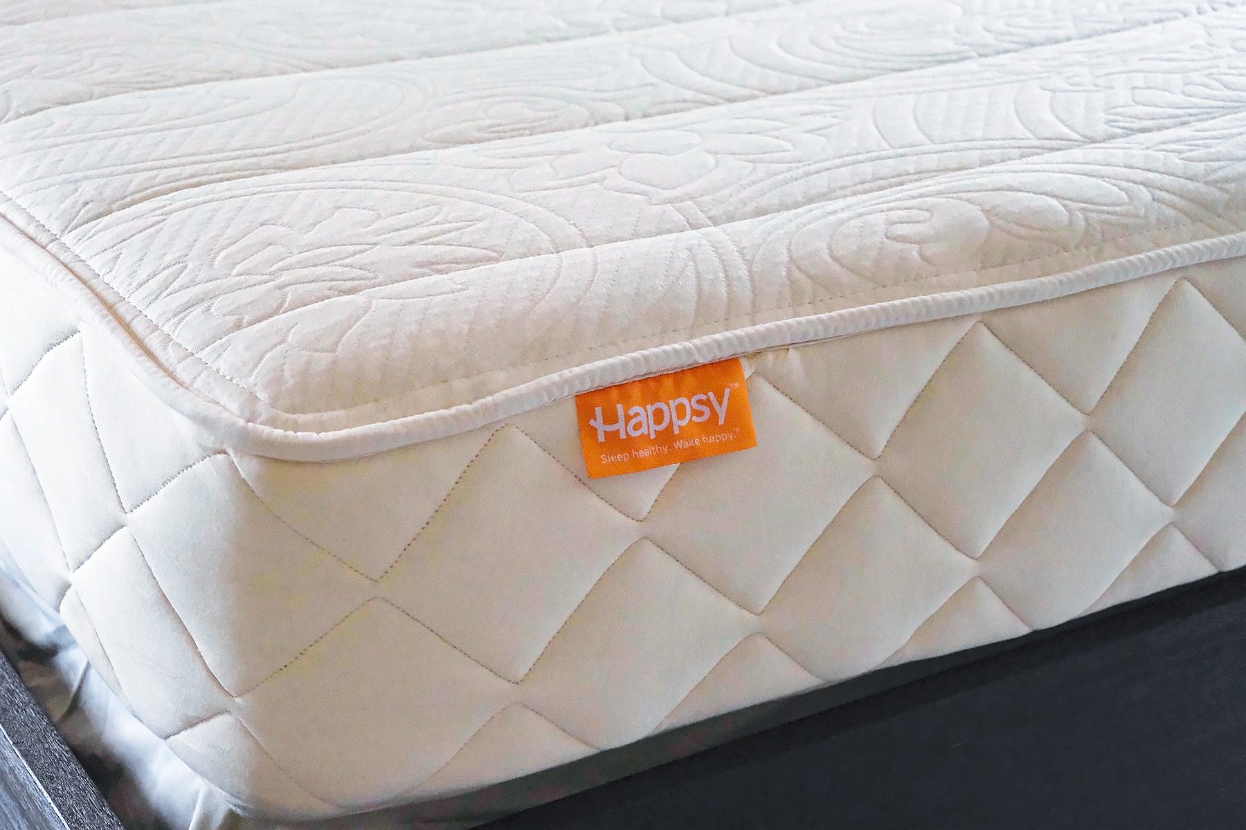 Close-up of a cream-colored, quilted mattress with an orange 
