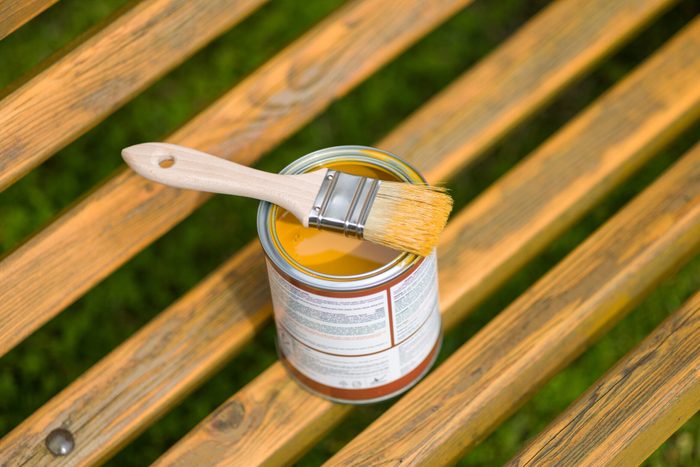 Paint Brush and Can on a Wooden Bench Outdoors