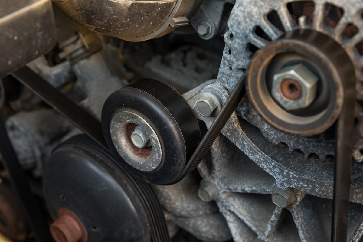 Serpentine drive belt tensioner idler pulley on automobile engine