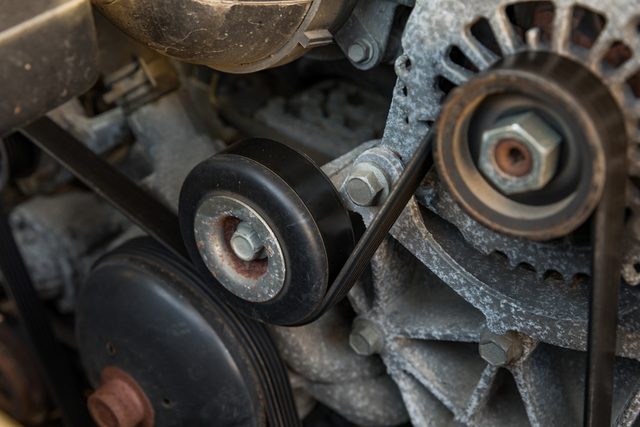 Serpentine drive belt tensioner idler pulley on automobile engine