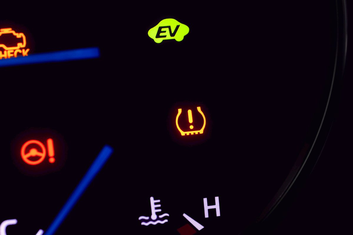 a close-up image of a car's dashboard; the dashboard is black with a variety of illuminated warning lights;