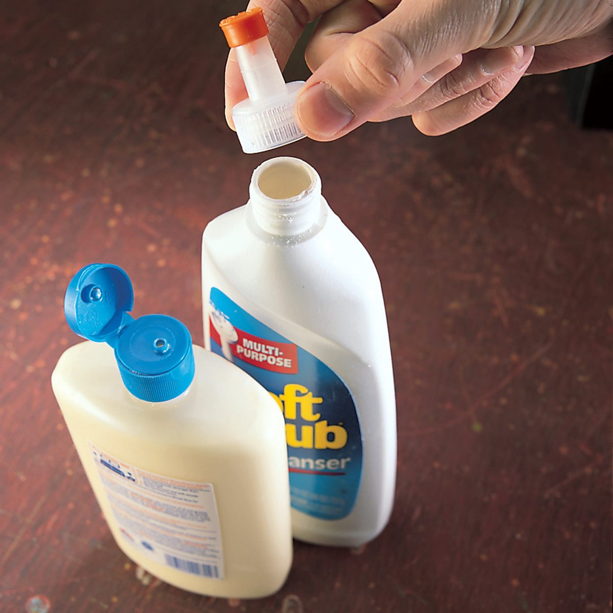 A person is holding the cap of an open plastic bottle labeled
