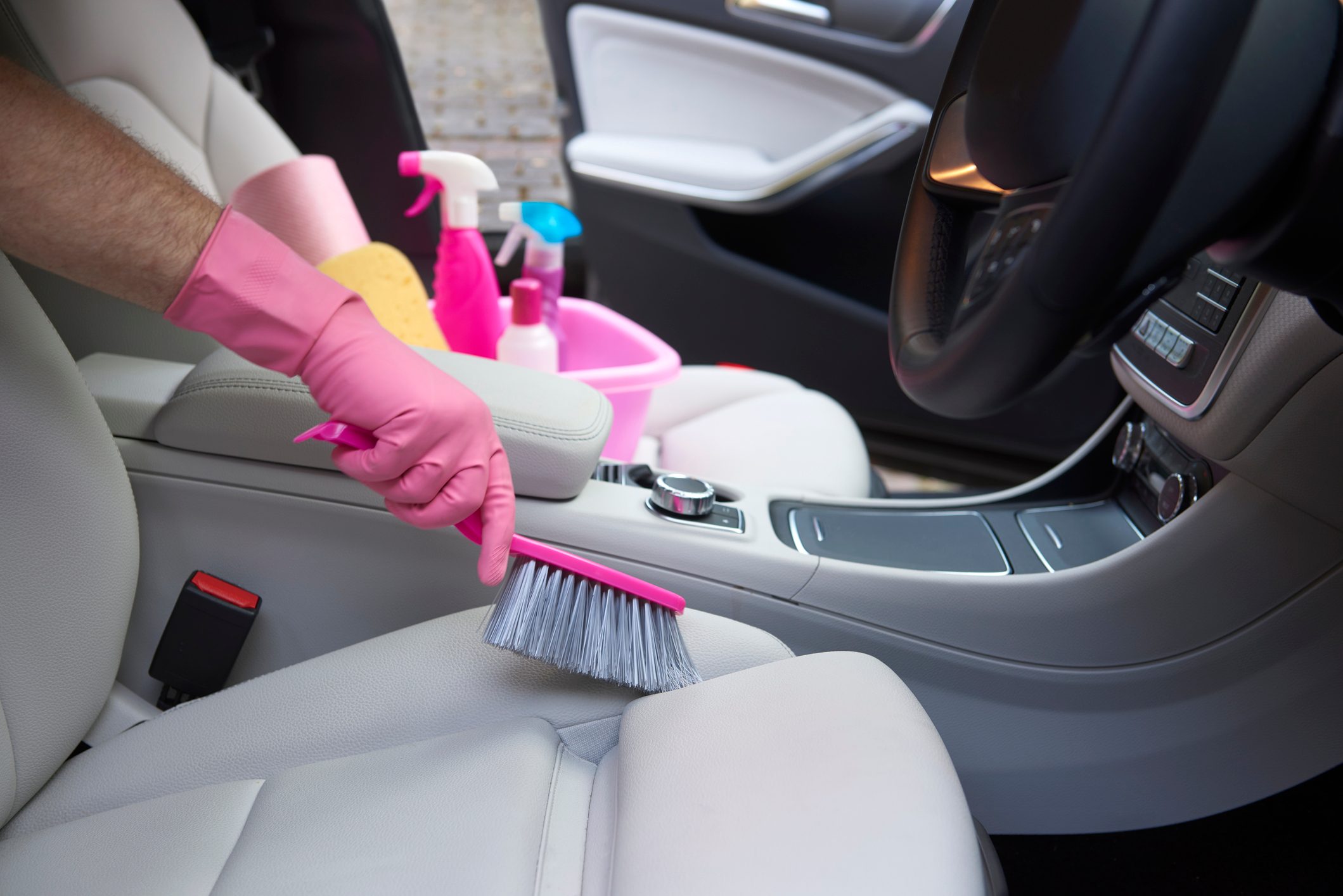 Person scrubbing car seat with a pink brush