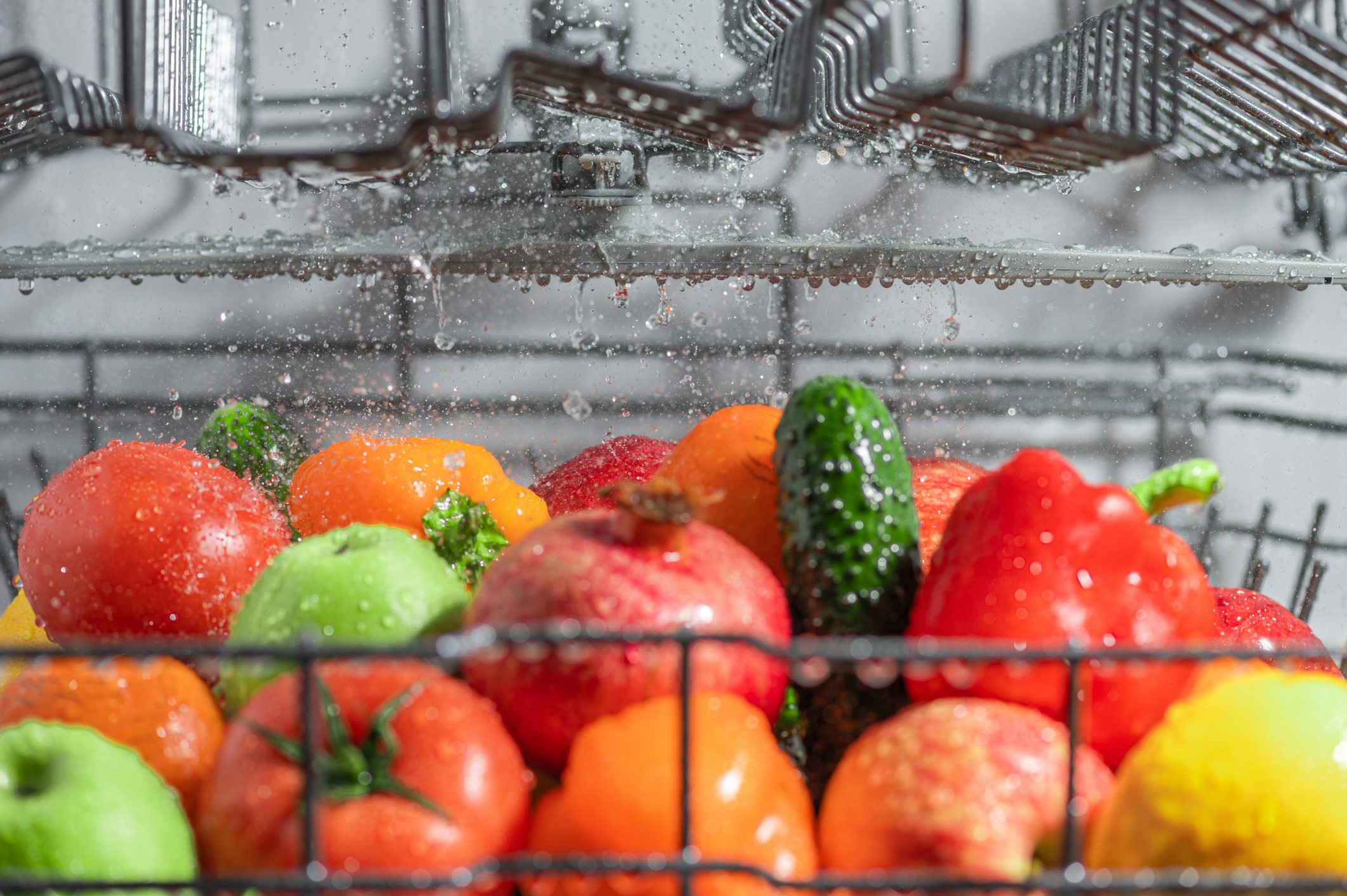Fruits and vegetables in a dishwasher rack being sprinkled with water