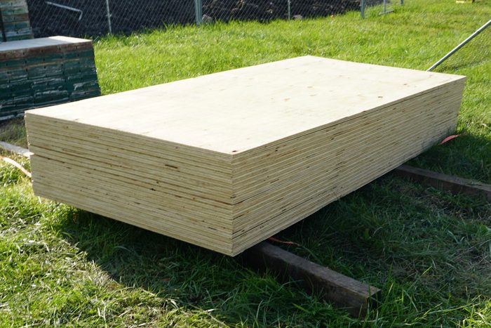Bundle of plywood sheets over the grass in backyard
