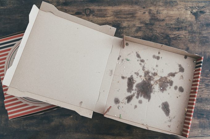 Empty, grease-stained cardboard pizza box on a dark surface