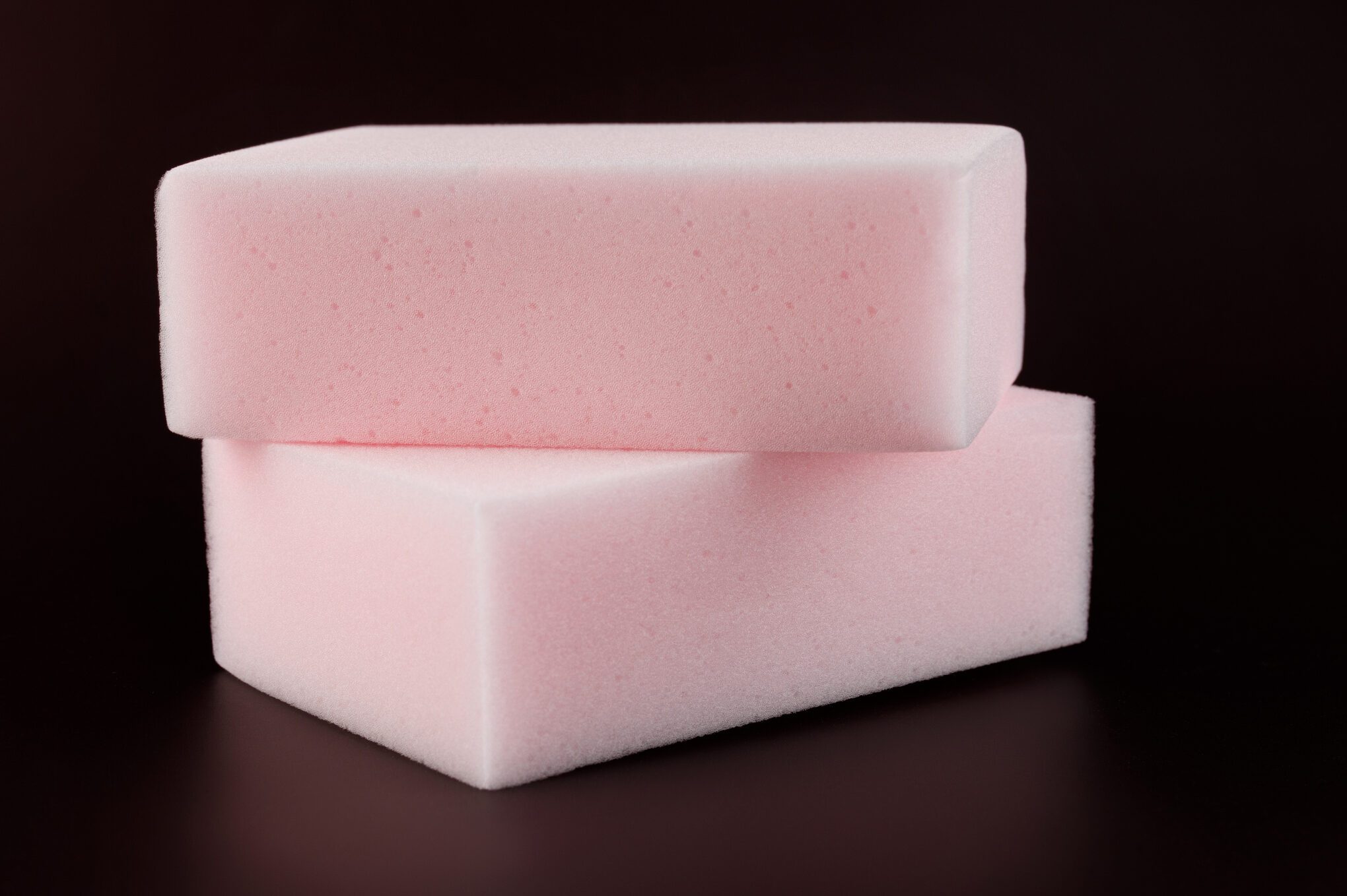 Melamine sponge on a dark red background.
