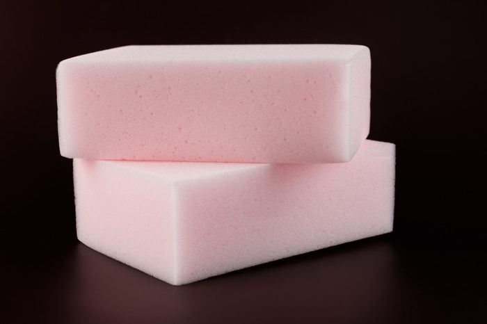 Melamine sponge on a dark red background.