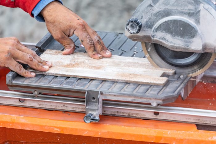 Worker using wet tile saw to cut wall tile
