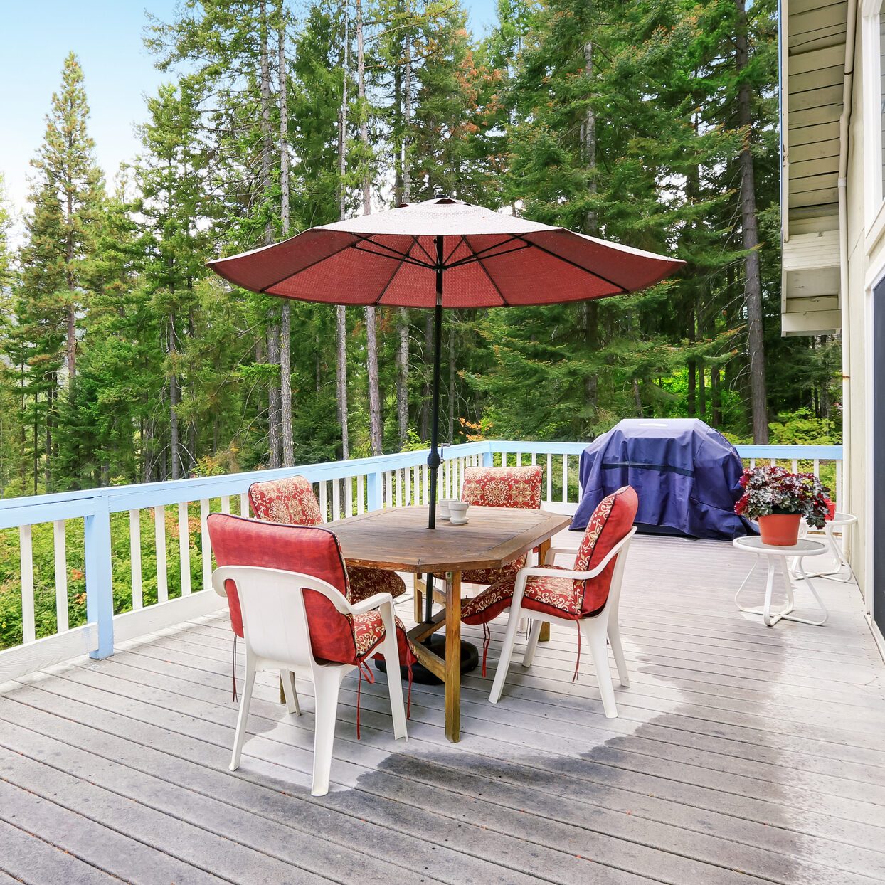 Wooden walkout deck . Furnished with red chairs and table