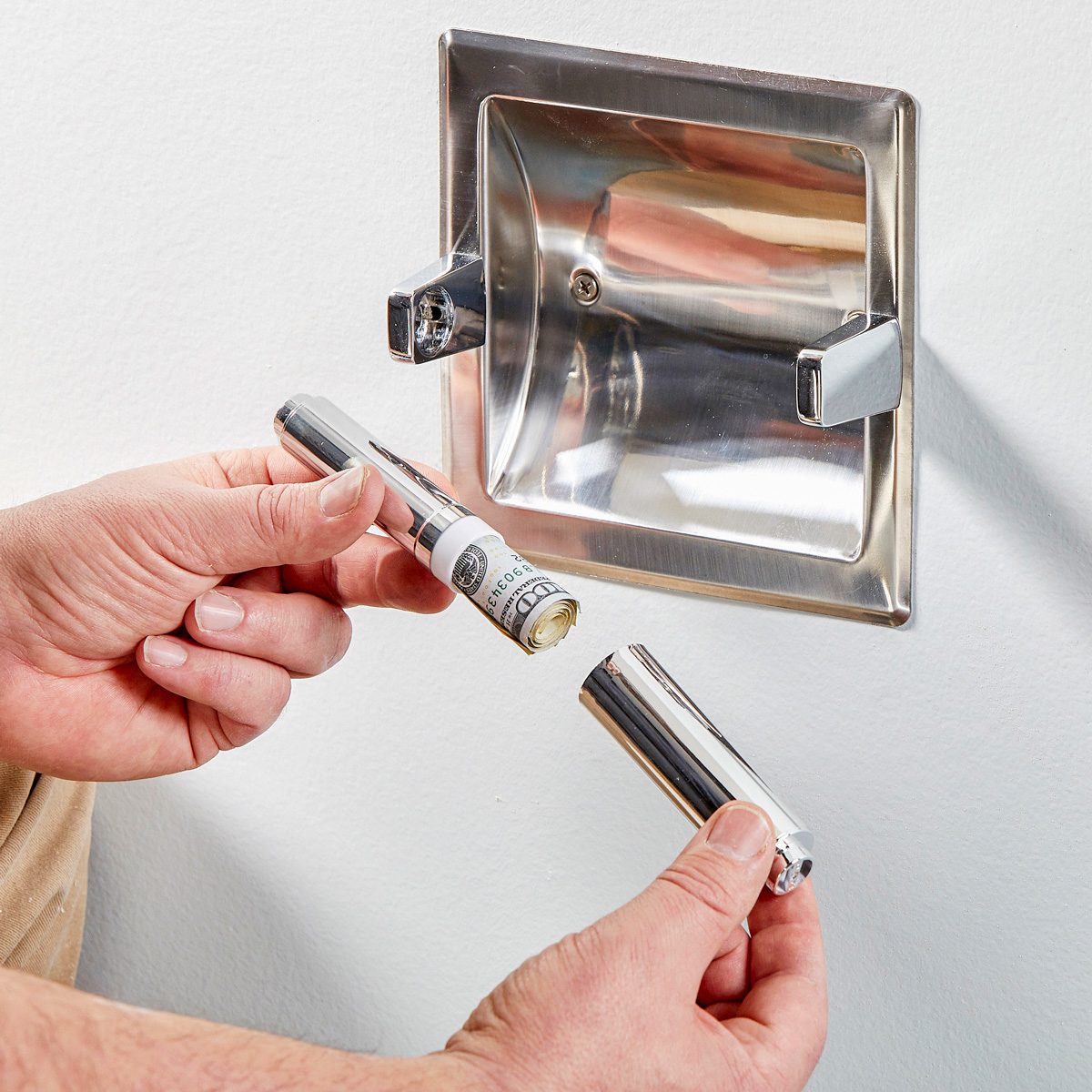 rolled up stack of bills being hidden in toilet paper roll spring bar