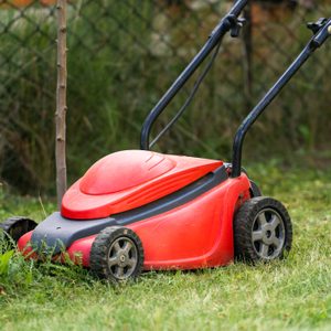 lawn mover at work on a green meadow at summertime