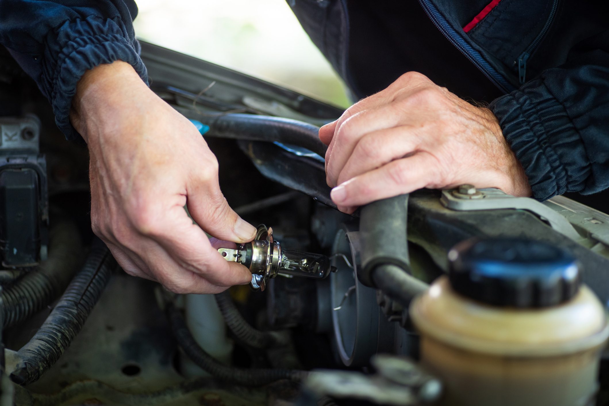 Man replacing the headlight of the car by hand