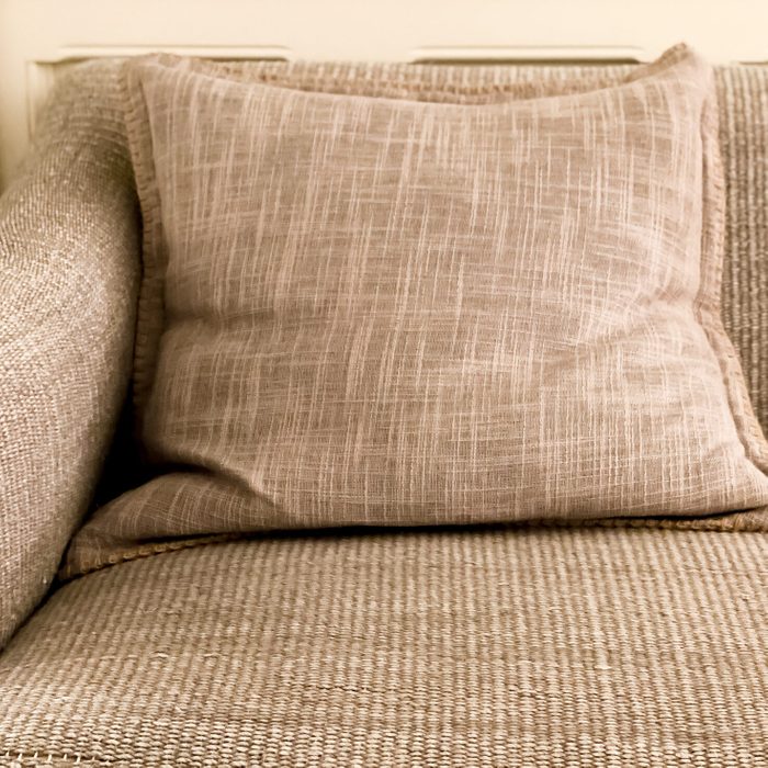 front corner view of textured gray sofa with decorative throw pillow