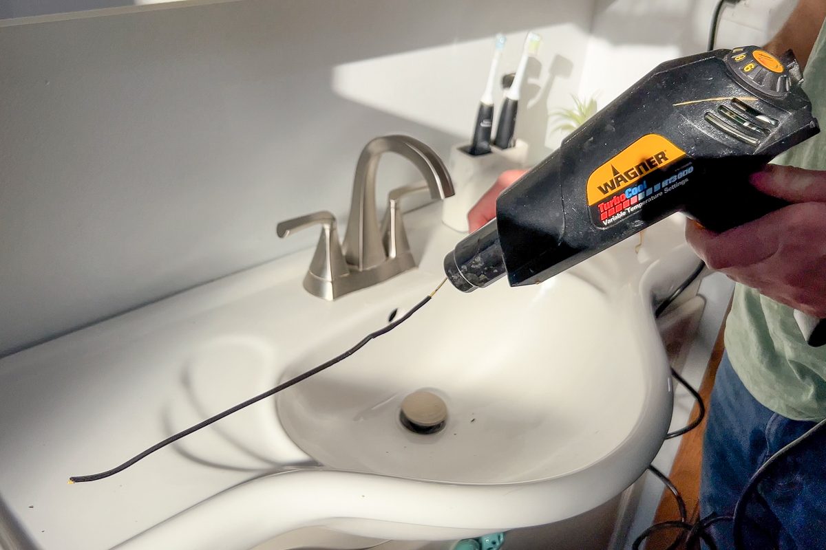 applying heat shrink tubing to the straightened hanger with a heat gun