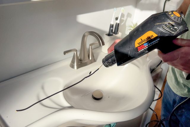 applying heat shrink tubing to the straightened hanger with a heat gun