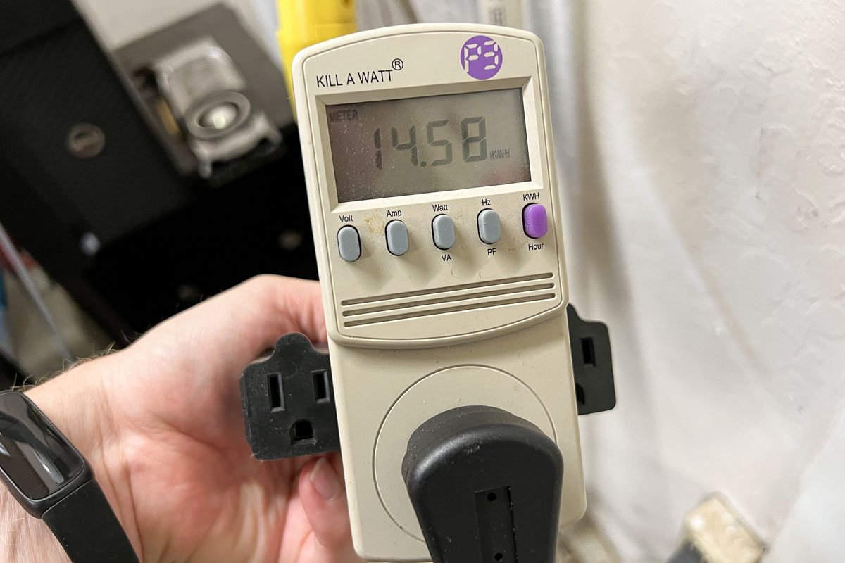 Person Holding A Kill A Watt Meter With Digital Display