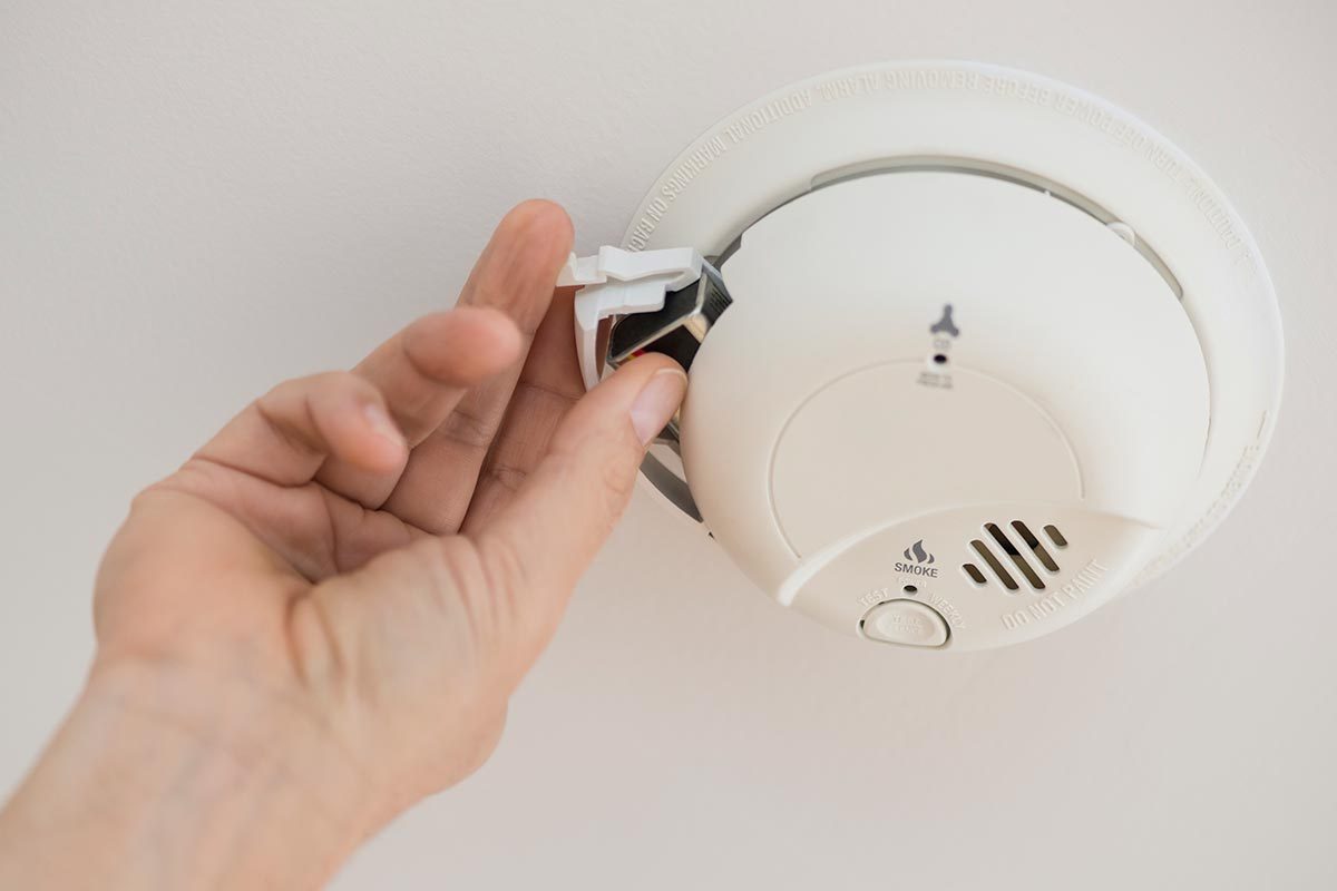 A person changng batteries of the fire alarm