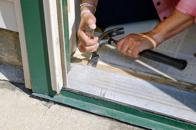 removing threshold of old door with hammer