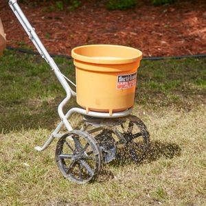 man using spreader to plant seeds