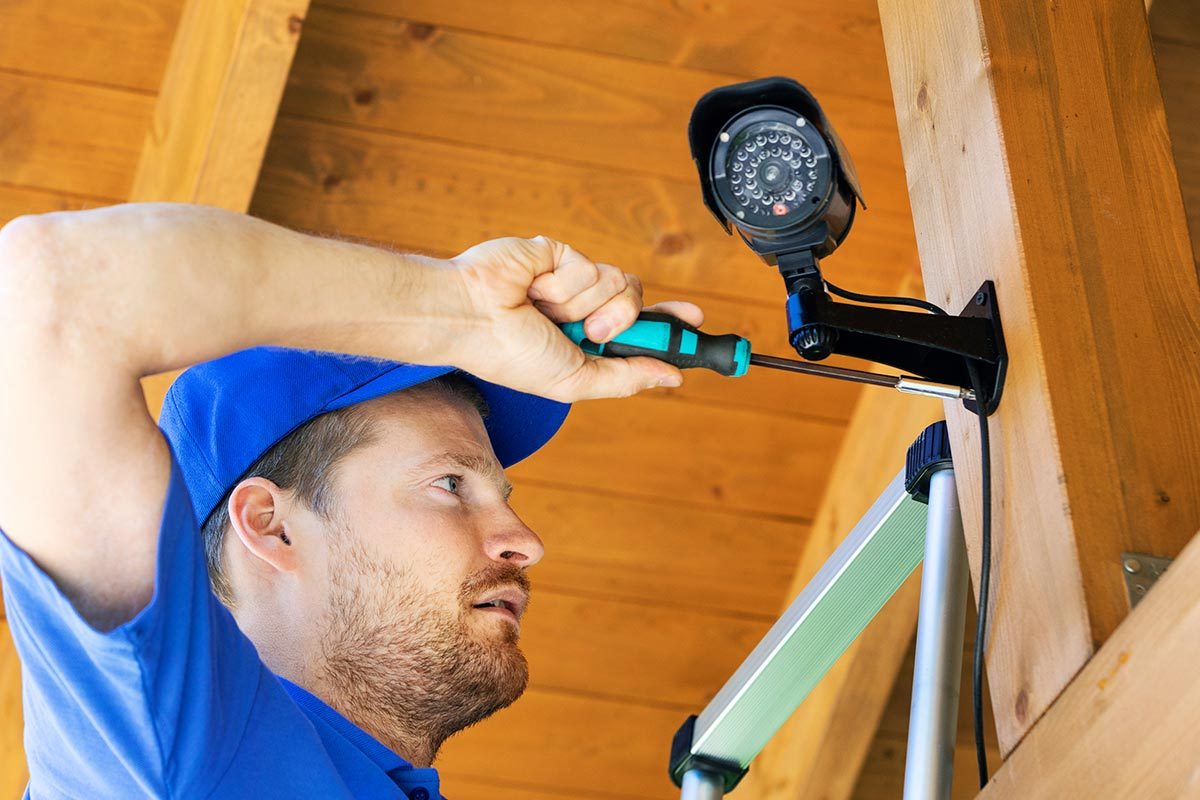 Technician installing surveillance camera in the house carport