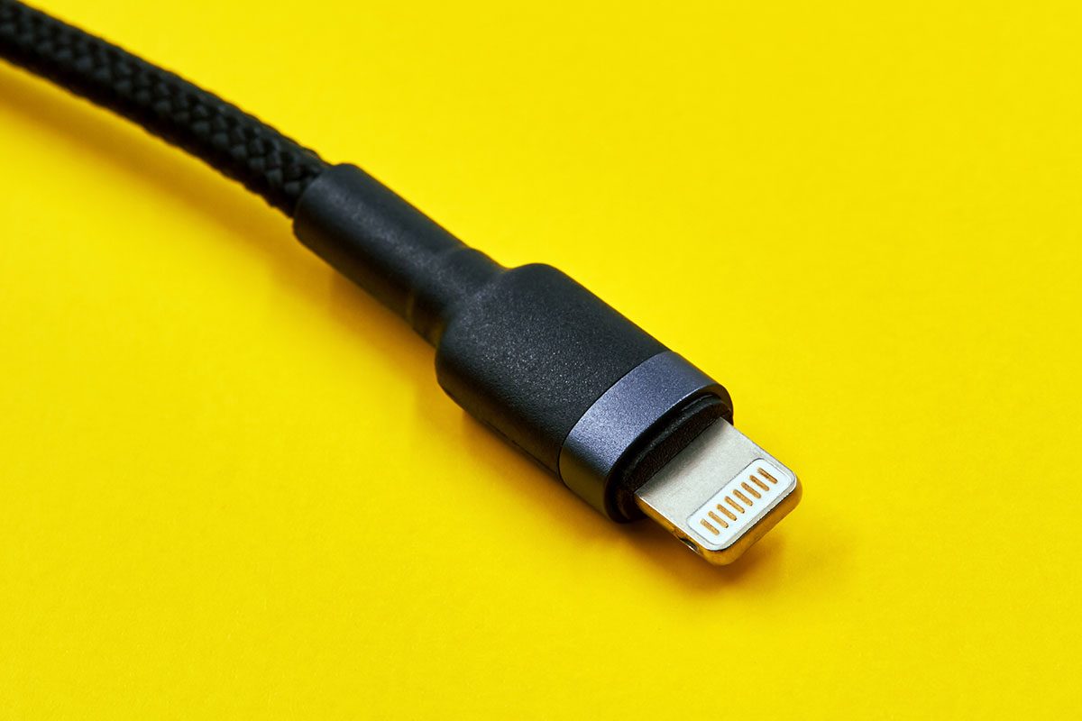 Black micro USB type c data and power cable plug on yellow background.