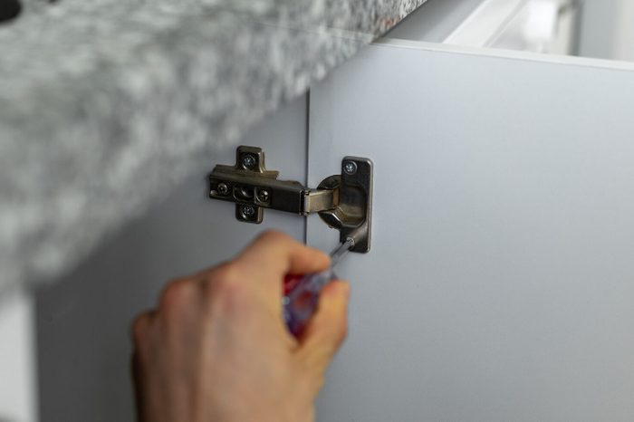 Repairman install cabinet hinge
