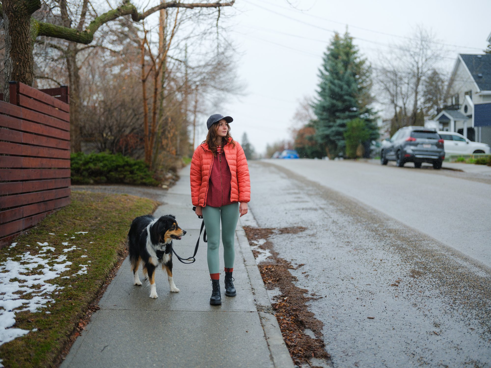 Woman walking her active dog in suburbs in springtime