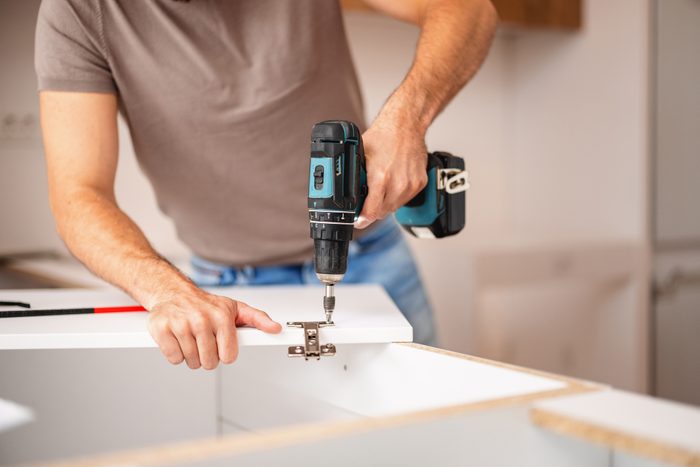 Carpenter Using Power Drill to Fit Kitchen Cabinet in New Apartment