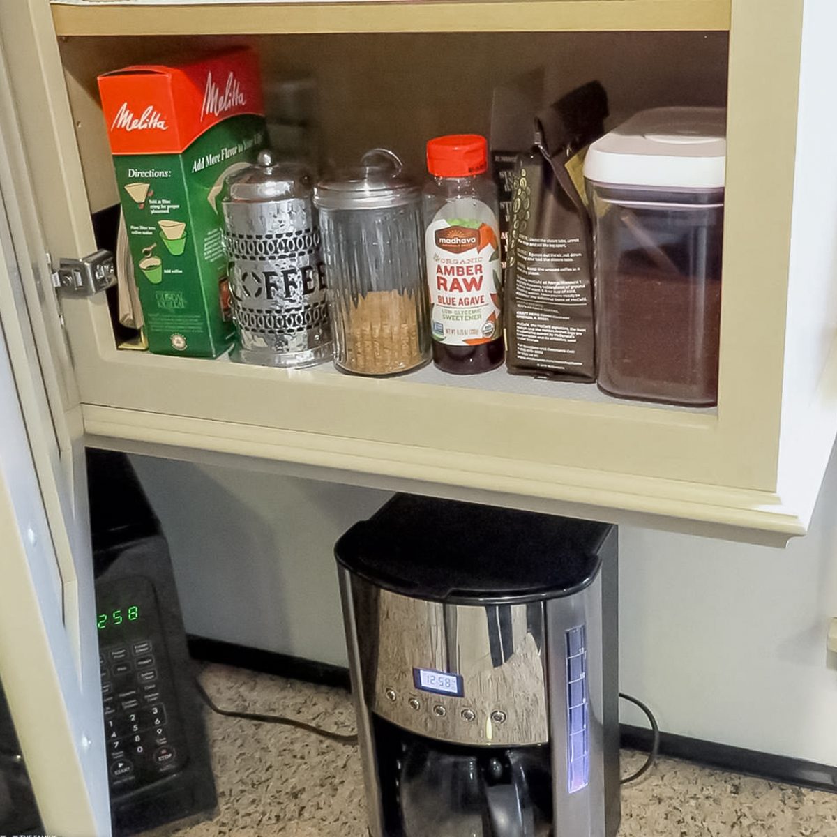 A kitchen cabinet with coffee filters, canisters labeled 