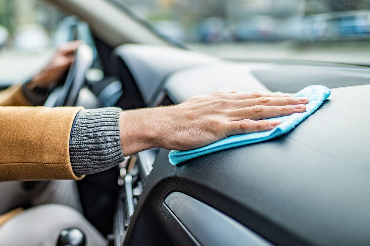 man cleaning his car interior with a micro fiber cloth.