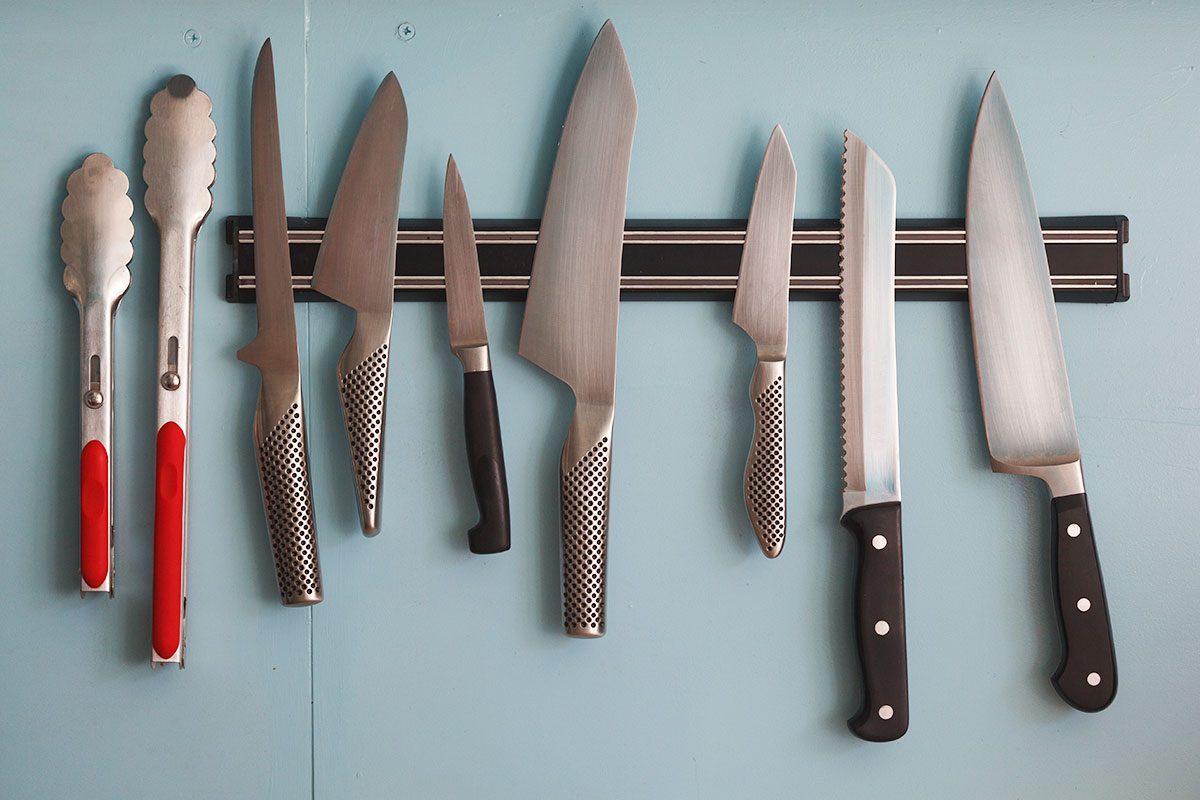 Kitchen knives and spoons mag-netted on wall.