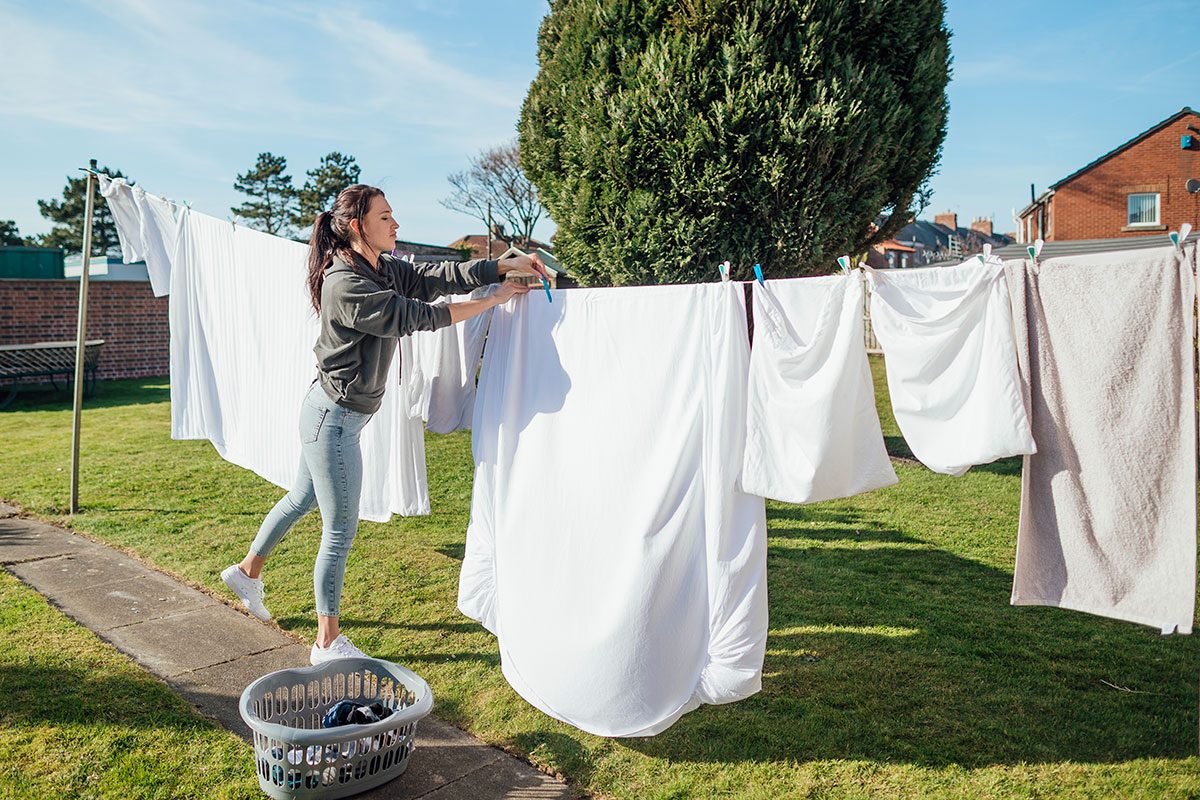 Female student doing her washing hanging it up and collecting it in her garden