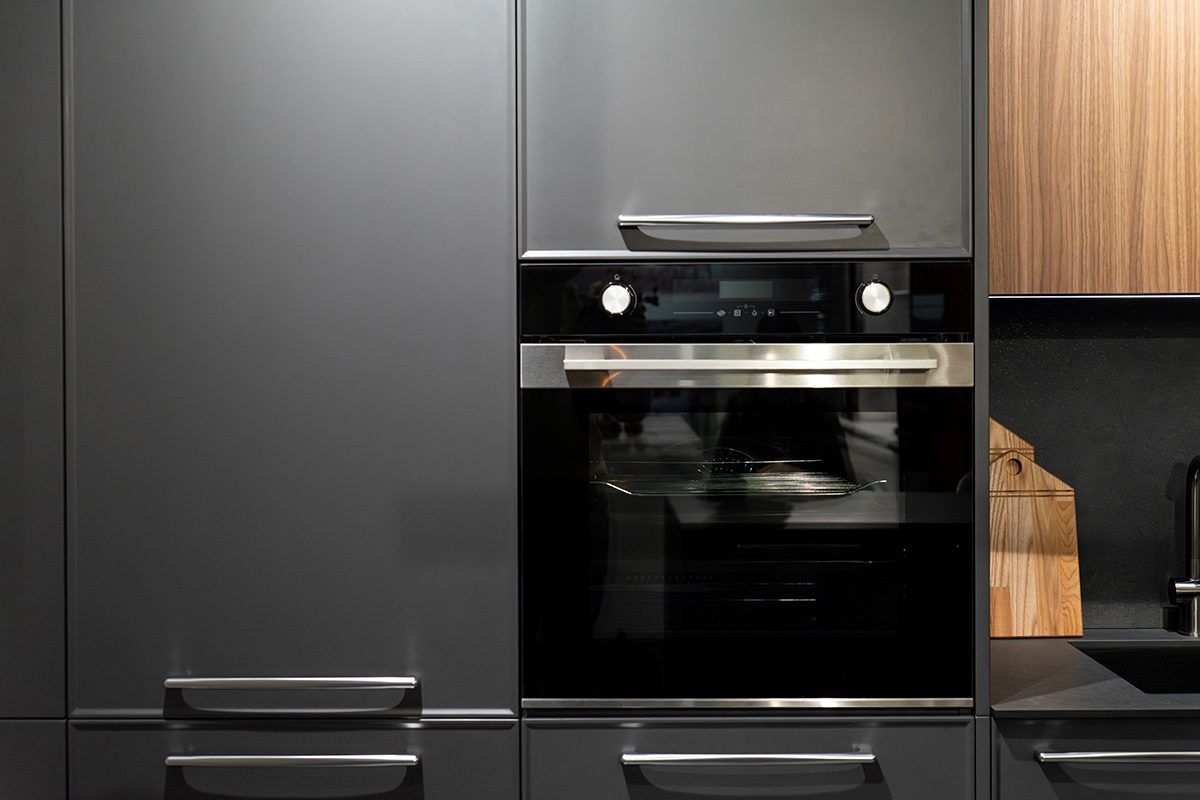 Built-in oven with sleek black finish and control knobs in minimalist kitchen
