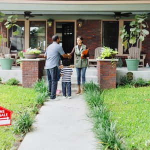 Lovely clients meet with their real estate agent in front of the house that they want to buy