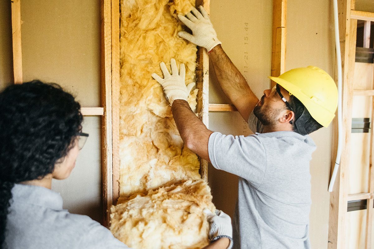 Construction workers fitting insulation in frame