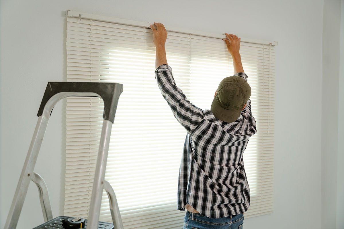 A professional blind installer adjusting sleek blinds in a modern house