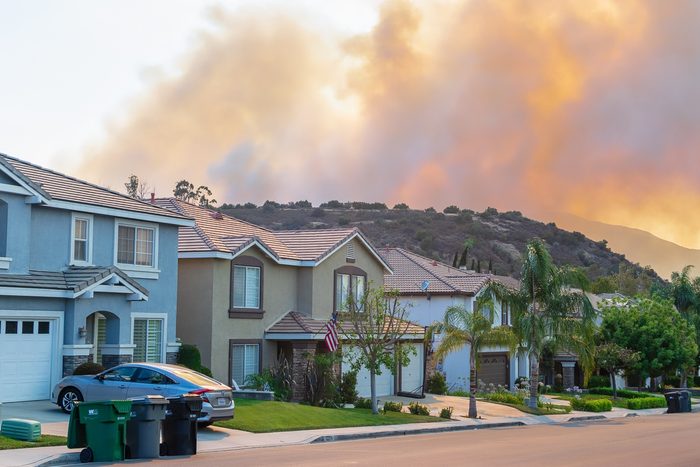 A wildfire burns and smoke rises in the forest near homes on the south city border close to the Cleveland National Forest