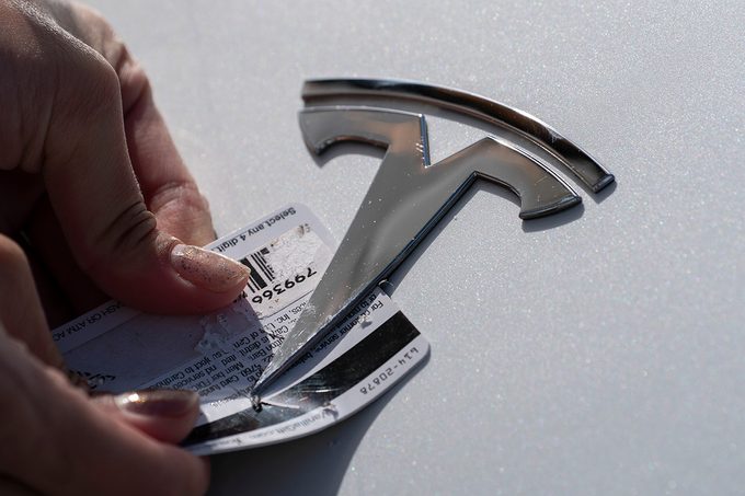 A Tesla emblem is being removed from a Tesla vehicle
