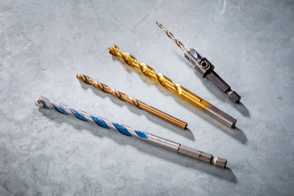 a close up view of four drill bits lying on a grey, textured surface