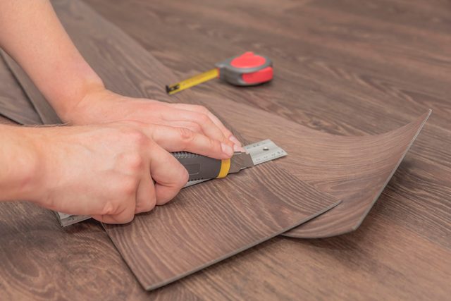 DIY vinyl flooring. Easy installation and cutting with a knife, Master cuts vinyl plank before installation, brown heated floor. Copy space