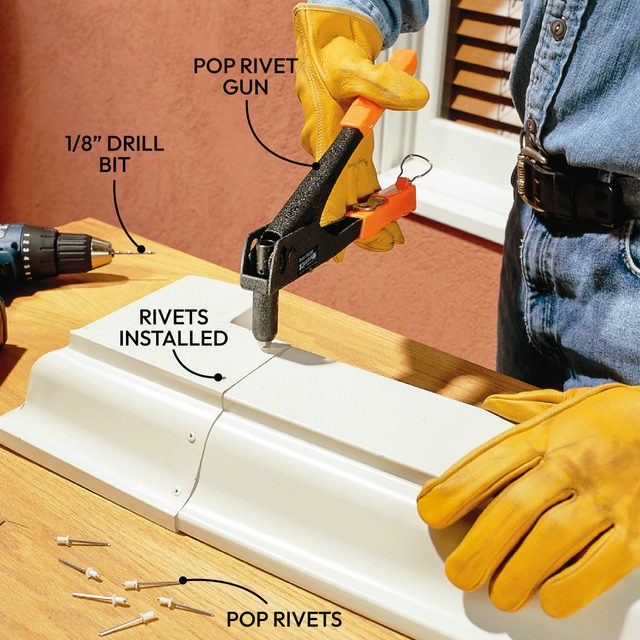A pop rivet gun applies rivets to a white metal seam on a wooden surface, with tools including a drill bit and rivets nearby.