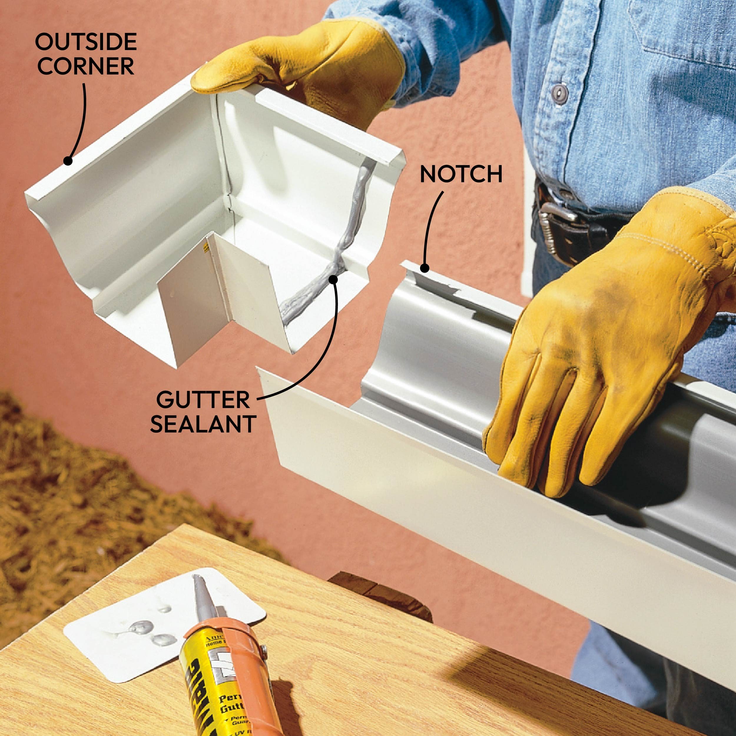 A person wearing gloves holds gutter pieces, aligning them for installation, with a backdrop of a peach-colored wall and a tube of sealant on a table.