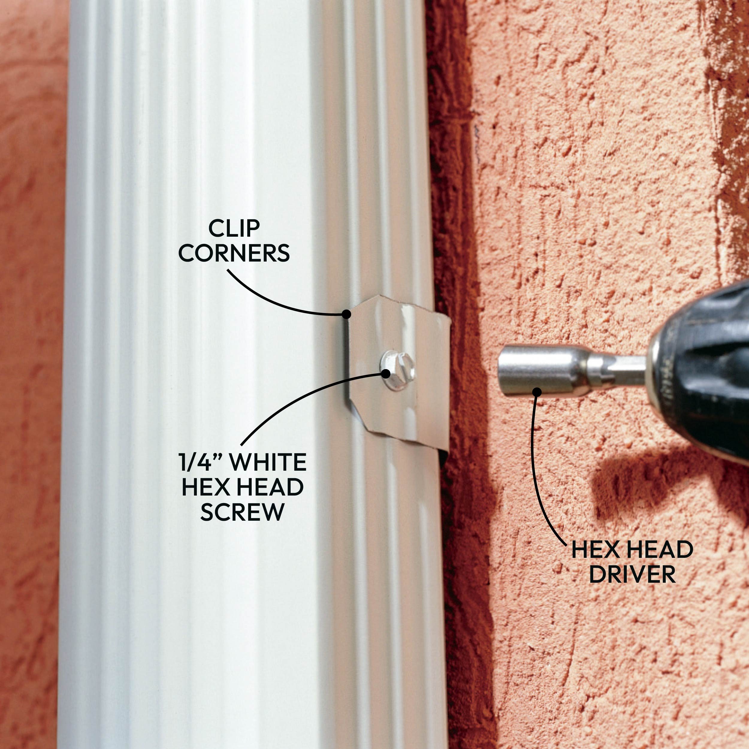 A metal clip secures corners of a white vertical object, with a hex head screw visible nearby and a hex head driver in action against a textured wall.