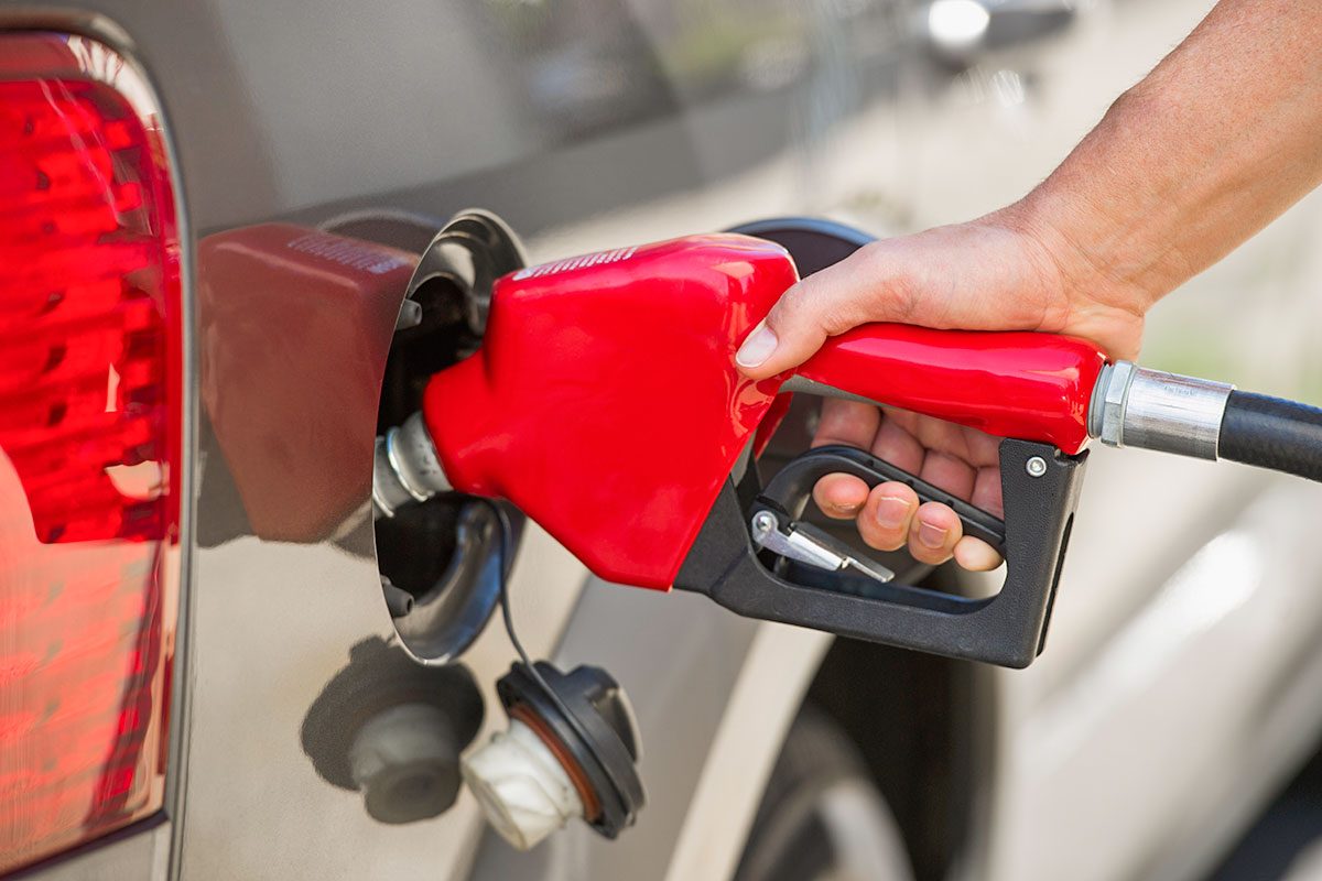 Hand holding fuel pump refueling car
