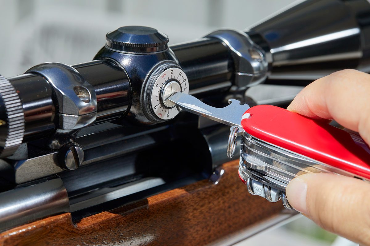 Closeup of a hand ficing the firearm with swiss army knife