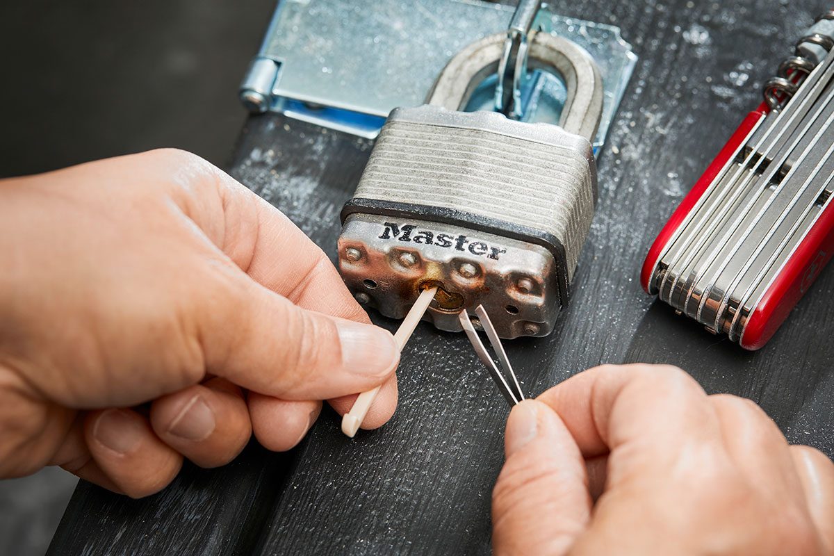 A person opening a lock using swiss army knife