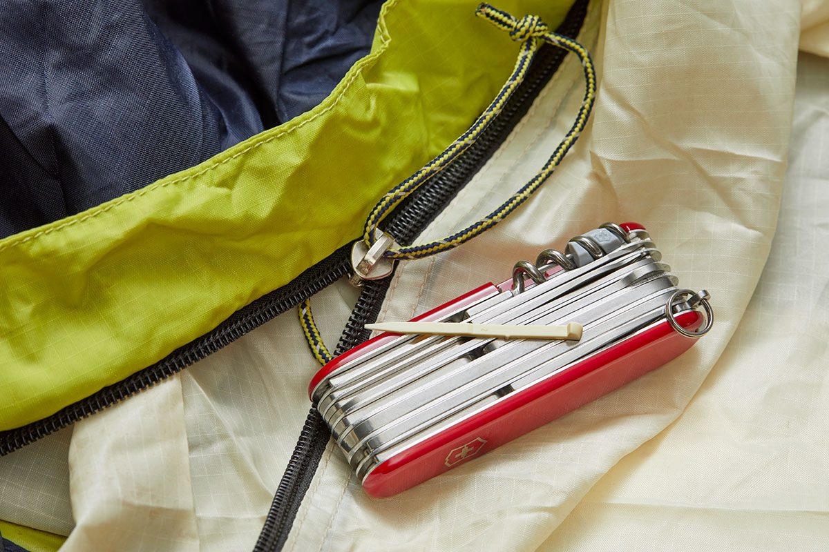 A closeup of a bag zipper and a swiss army knife