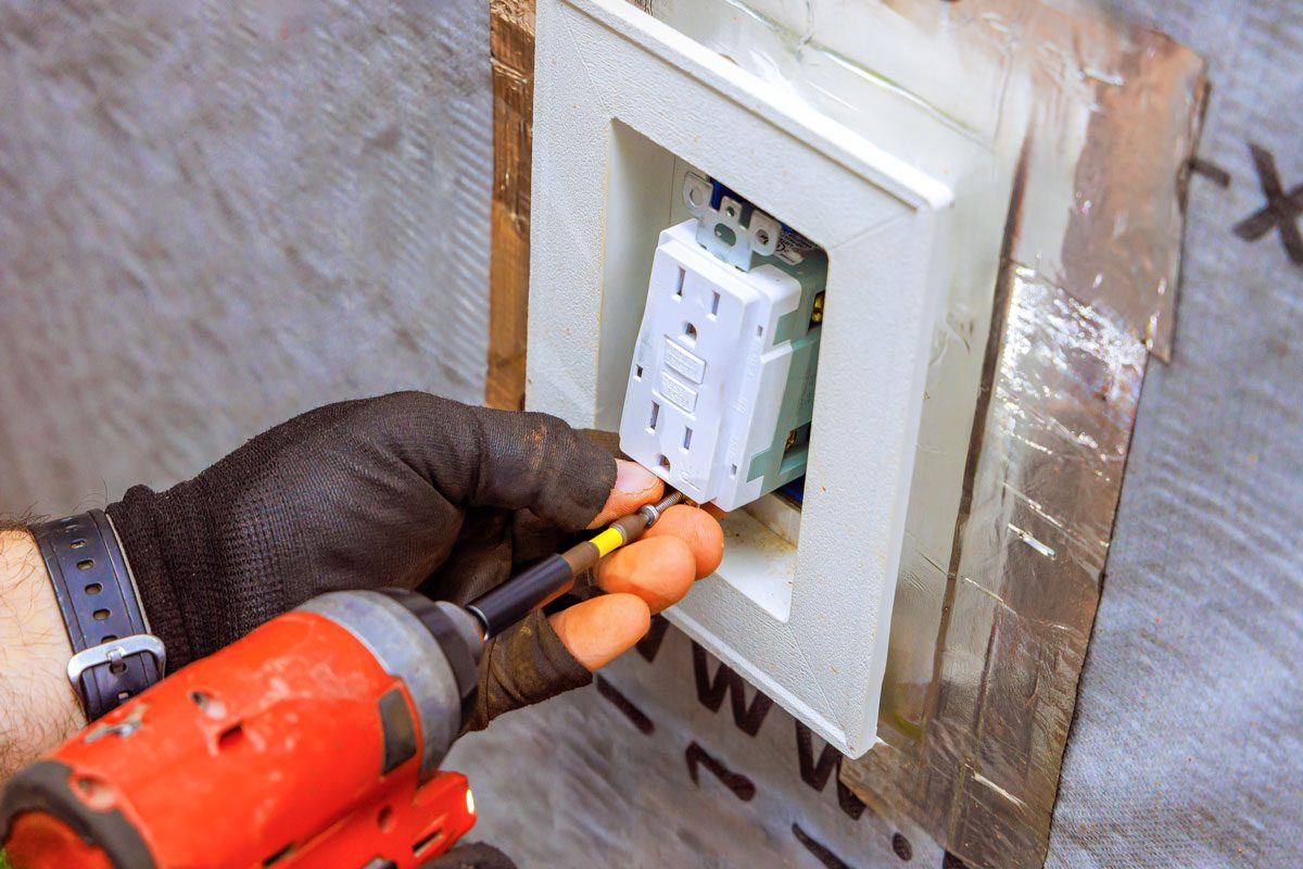 Electrician Installing An Outlet In Residential Home